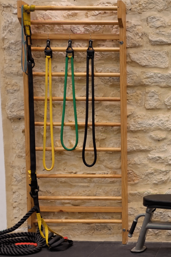 Espaldera anclada a pared con elásticas colgadas en clínica de fisioterapia
